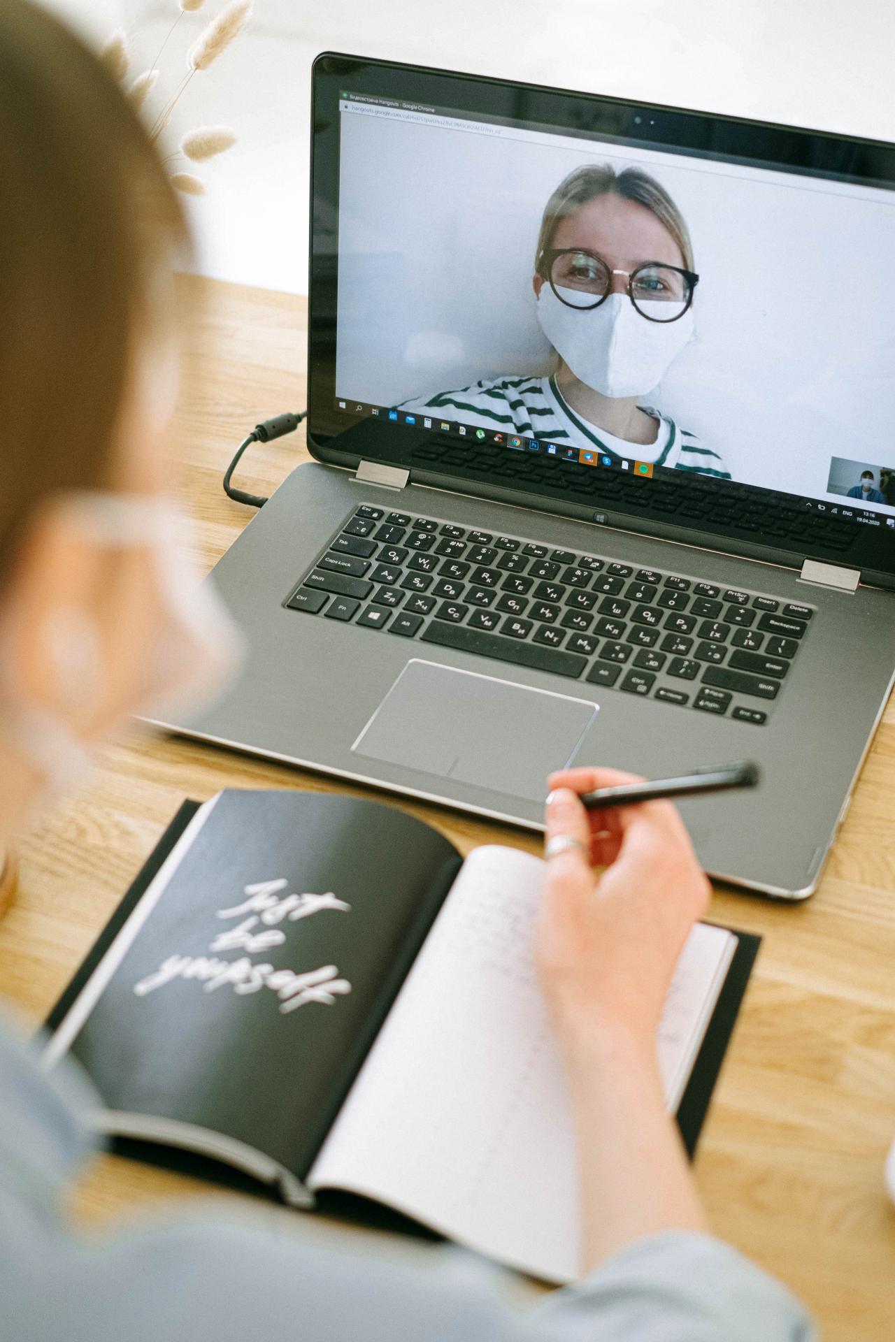 Person vor Laptop mit Notizblock während Coronazeit
